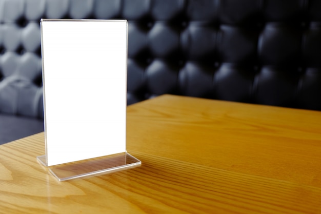 Mock up menu frame standing on wood table in bar restaurant cafe. space for text.