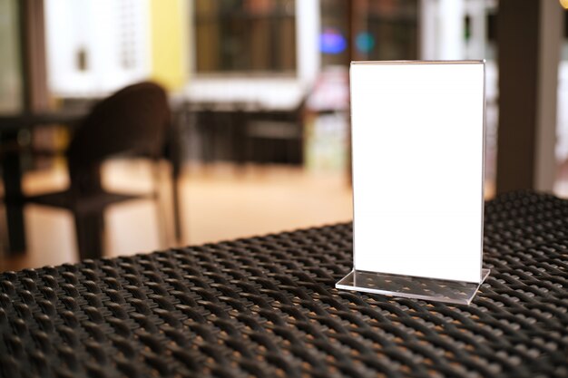 Mock up menu frame standing on wood table in bar restaurant cafe. space for text.