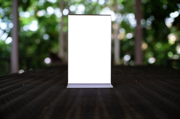 Mock up menu frame standing on wood table in bar restaurant cafe. space for text.