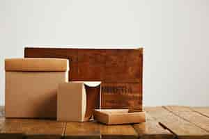 Free photo mockup blank beige paper boxes next to a retro rough brown wooden crate isolated on white