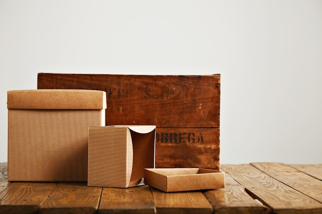 Mockup blank beige paper boxes next to a retro rough brown wooden crate isolated on white