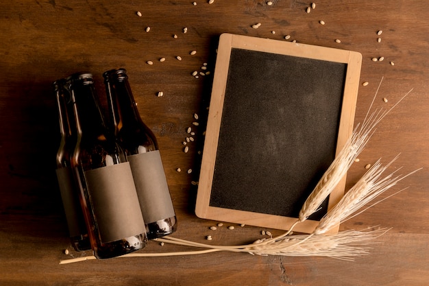 Mockup of brown bottles of beer with blackboard on wooden table