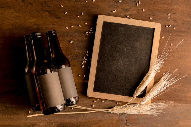 Mockup of brown bottles of beer with blackboard on wooden table