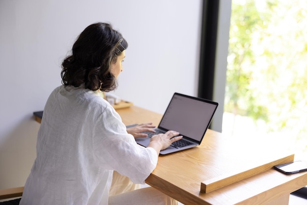 Free photo mockup of brunette woman working on laptop at home