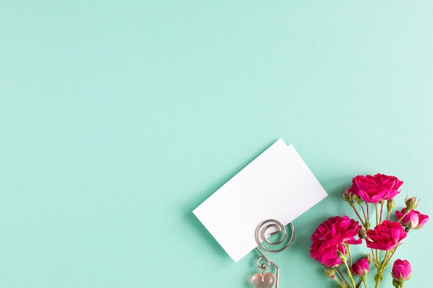 Mockup business cards on a colored background and a rose flower, copyspace, topview.