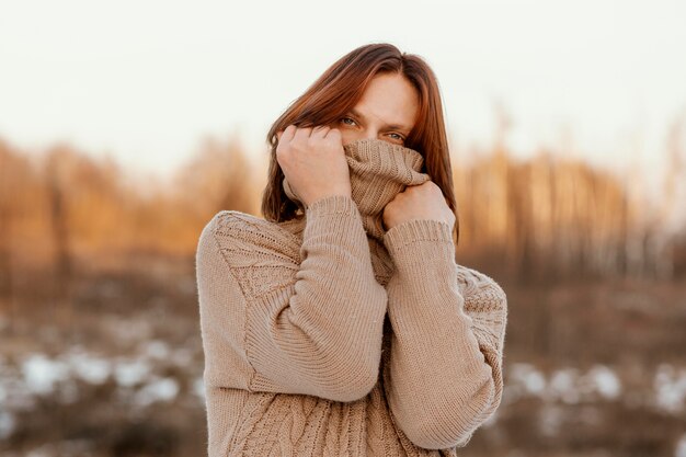 Model covering face with a beige sweater