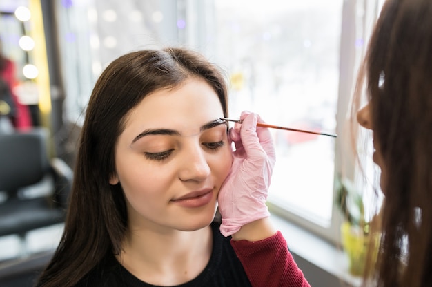 Model is doing eyebrow painting procedure in beauty salon