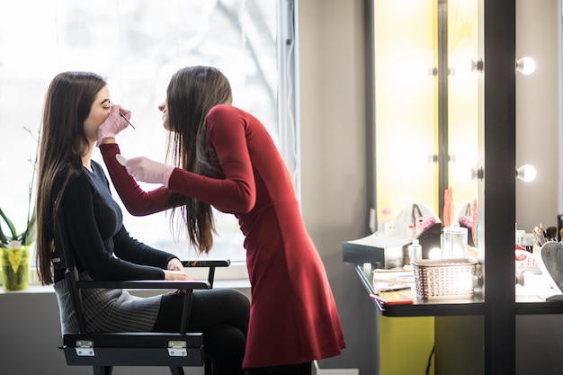 Model is sitting on high chair during professional make-up procedure