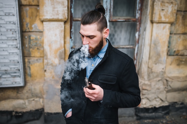 The model vaper vaping a vaporizer outdoors. Safe smoking. Young vaper.