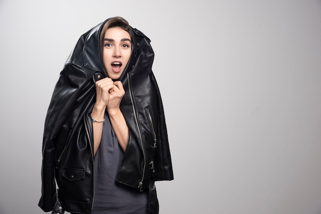 model wearing black leather jacket over a gray background.