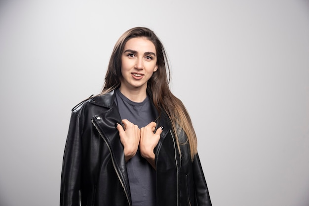 Model wearing black leather jacket over a gray background.