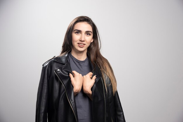 Model wearing black leather jacket over a gray background.