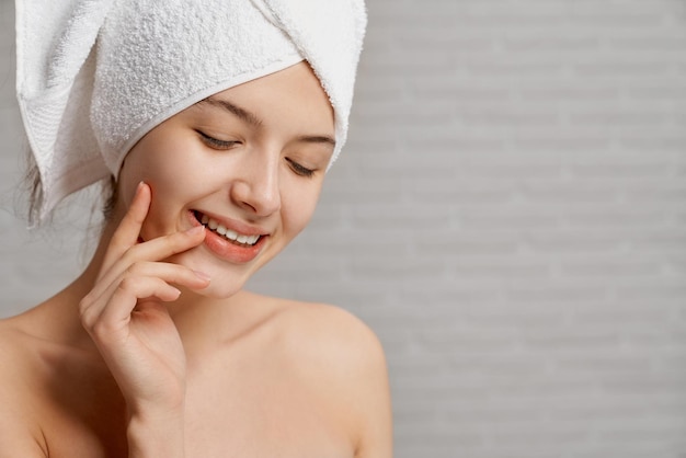 Model in white towel on head touching face