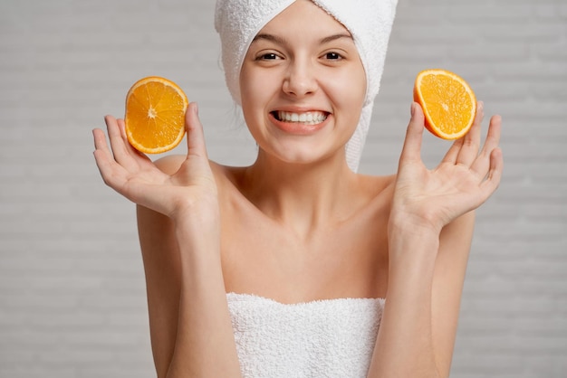Model with bare shoulders holding two pieces of orange