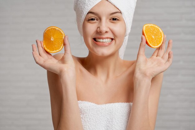 Model with bare shoulders holding two pieces of orange