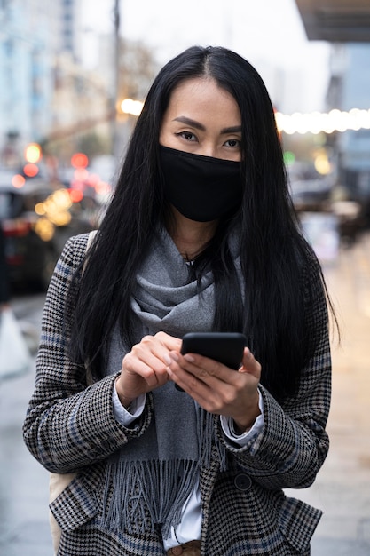 Model with mask holding smartphone