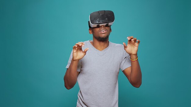 Modern adult having fun with vr glasses game on camera, playing with 3d visual simulation. Millennial man using virtual reality goggles with interactive vision and futuristic augmented software.