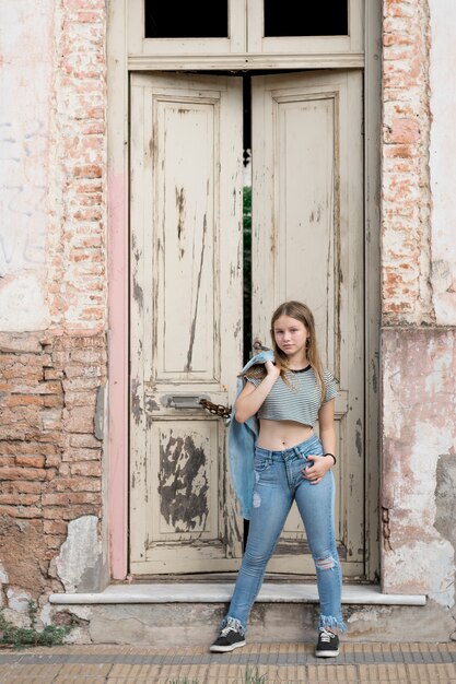Modern attractive teenage girl posing near weathered door