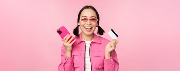 Modern beautiful asian girl laughing and smiling with mobile phone credit card shopping online payin