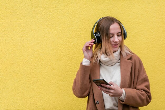Modern blonde woman listening to music on headphones with copy space