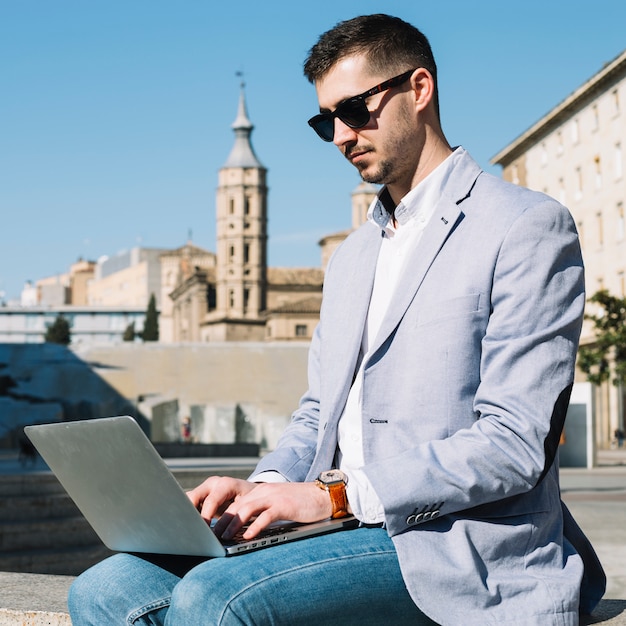 Modern businessman using laptop outdoors