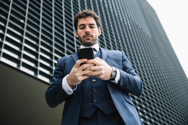 Uomo d'affari moderno usando smartphone all'aperto