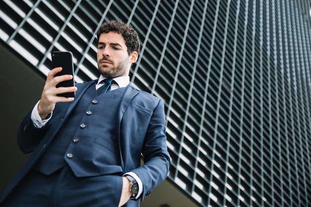 Foto gratuita uomo d'affari moderno usando smartphone all'aperto