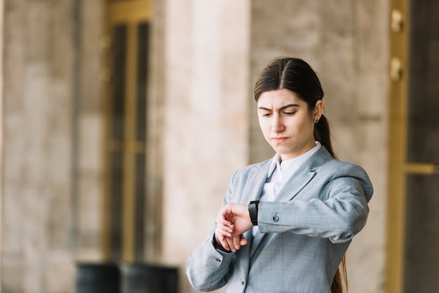 Modern businesswoman looking at watch outdoors