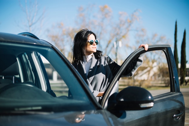 Modern businesswoman standing next to car