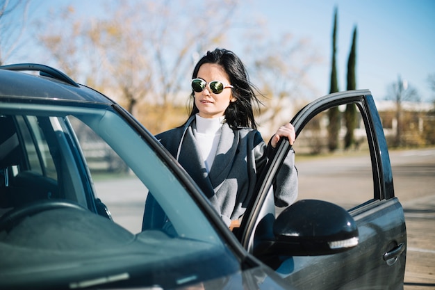 Modern businesswoman standing next to car