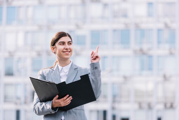 Modern businesswoman with clipboard outdoors