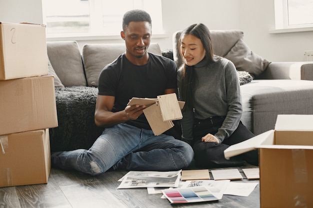 Modern couple is choosing colors for furniture. Cute couple sitting on the floor in their new home.