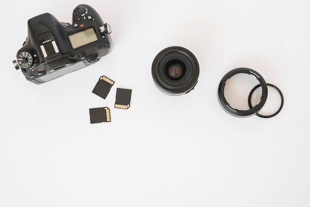 Modern dslr camera; memory cards and camera lens with extension rings on white backdrop