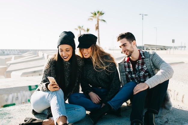 Free photo modern friends sitting on concrete blocks