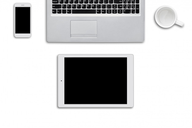 白い表面に横になっている現代のガジェット。ラップトップコンピューター、タブレット、スマートフォン、白い壁に白い空のカップ。ネットサーフィンや仕事に必要な最新のデバイスの平面図。技術