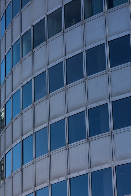 Modern glass skyscraper background with sky and clouds reflection