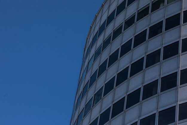 Modern glass skyscraper background with sky and clouds reflection