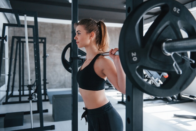 Modern gym. Photo of gorgeous blonde woman doing exercises at her weekend time