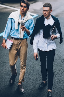 현대 라이프 스타일. 소셜 커뮤니케이션 우정. 도시의 거리를 걷고 있는 두 명의 멋진 남자.