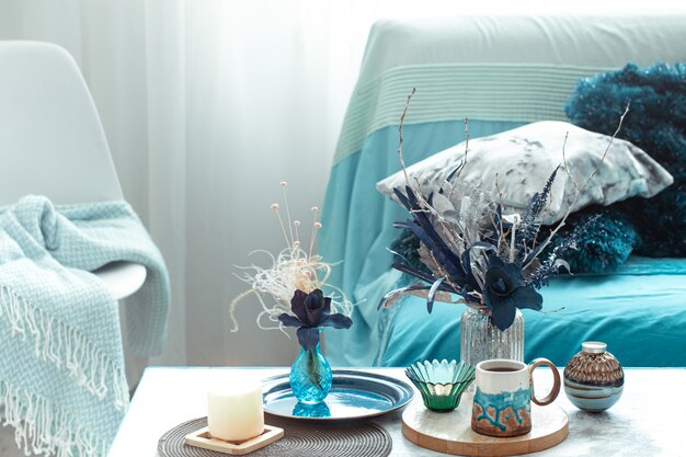 Modern living room, with artificial flowers in a vase and home decor items on wooden light table.