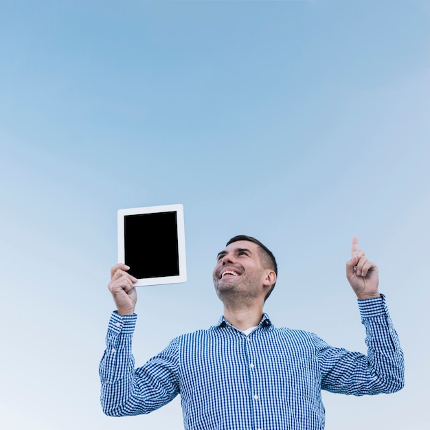 Free photo modern man pointing up with tablet