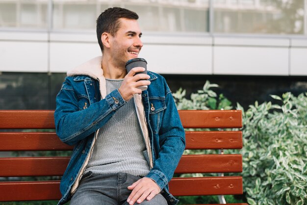 Modern man sitting on bench in urban environment