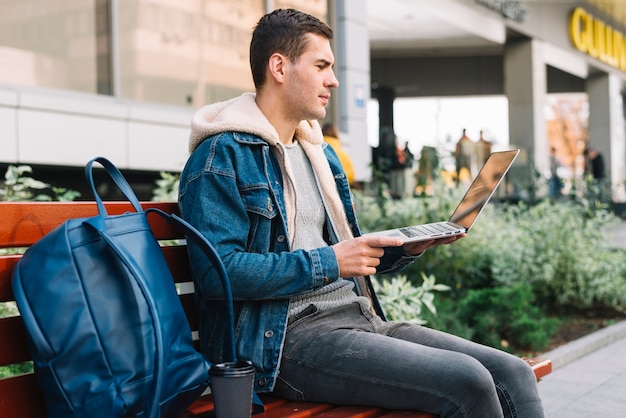 Modern man sitting on bench in urban environment