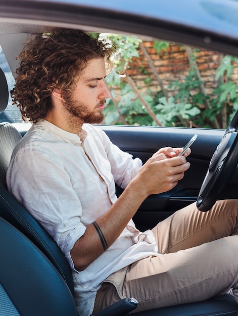 Modern man using smartphone in car