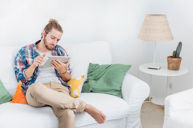 Foto gratuita uomo moderno che utilizza la tabella sul divano