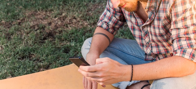 Uomo moderno con lo smartphone in giardino