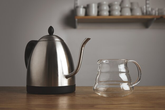 Modern metallic teapot with transparent pot for filtered coffee in thick wooden table in cafe shop