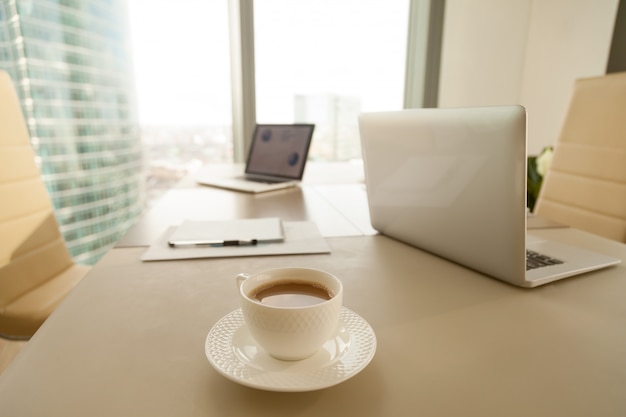 Modern office workplace, coffee cup, laptops on conference negot