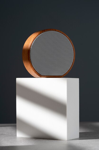 Foto gratuita altoparlante wireless rotondo moderno dal design elegante presentato su un podio geometrico