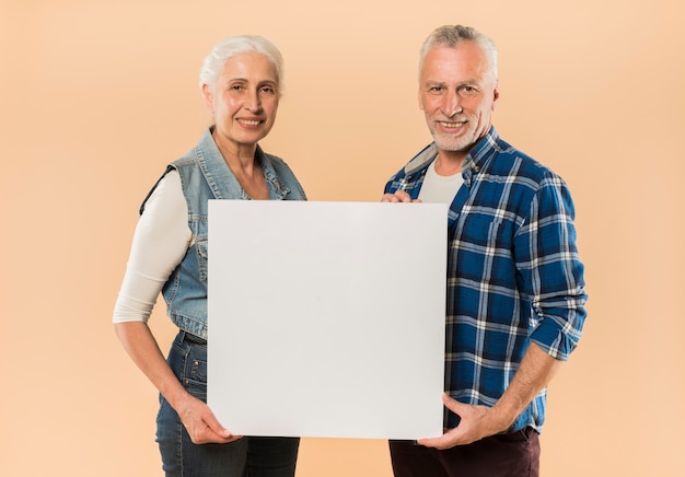 Modern senior couple holding board template